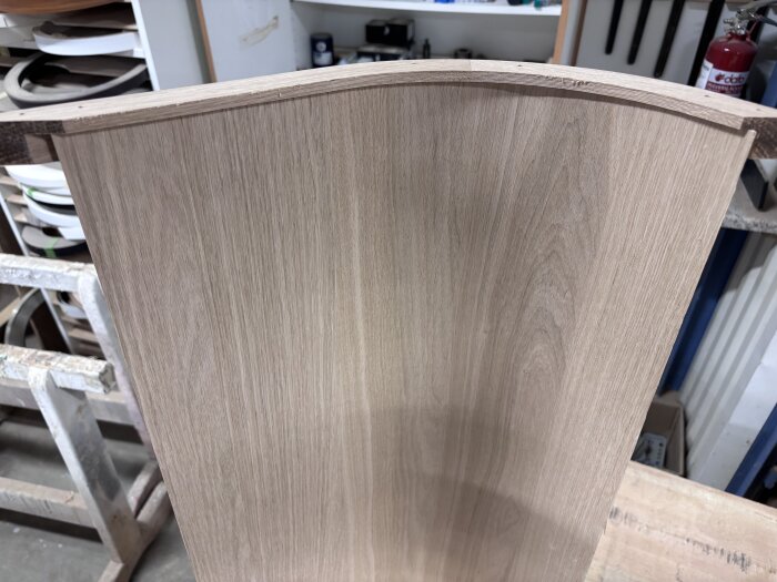 Falsad kantlist av trä redo för limning i ett snickeriverkstadsmiljö, med verktyg och material i bakgrunden.