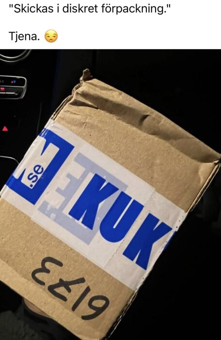 En kartong märkt med stort blått text, fotograferad inuti en bil, med texten "Skickas i diskret förpackning" skrivet ovanför.