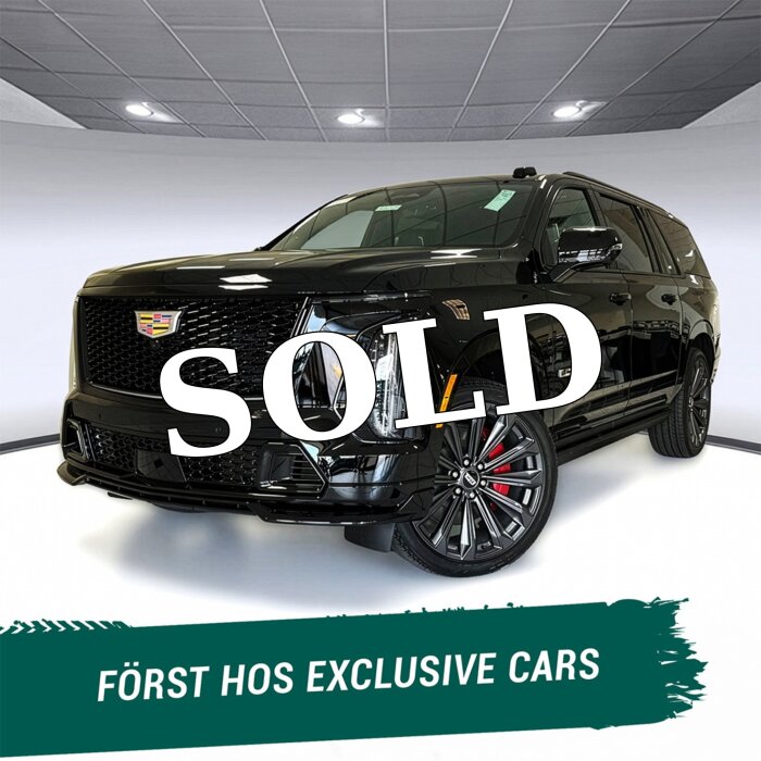 Svart Cadillac SUV med "SOLD" skrivet över bilden, tagen i exklusivt showroom med texten "FÖRST HOS EXCLUSIVE CARS" i förgrunden.