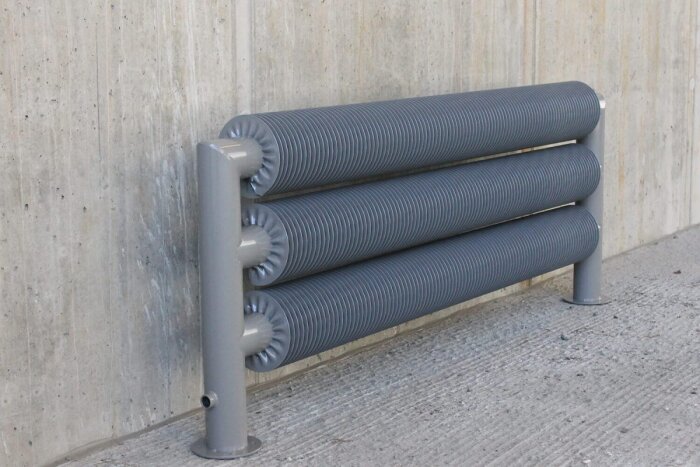 Grå ribbat rör längs betongvägg, del av byggprojekt.