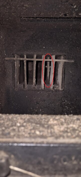 Insidan av en kamin med en inringad del som saknar spjäll och snurrbar stång.