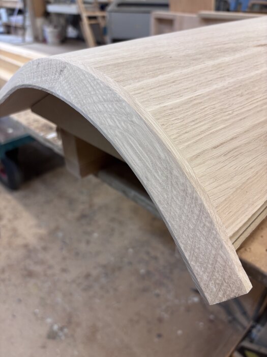 Baksidan av en träskåpslucka med rundad kant, skapad med 45-graders kullagerfräs, visas på ett snickeribord.