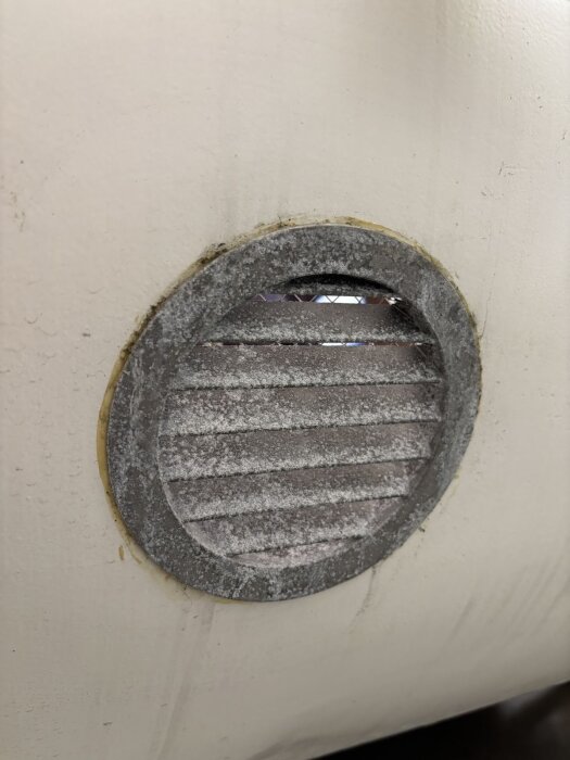 Oxiderat ventilgaller i aluminium på vit yta, behöver rengöras och målas för att förhindra ytterligare oxidation.