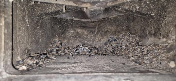 Insidan av en asklåda med aska och sot, visar inga spår av en lucka eller spjäll.
