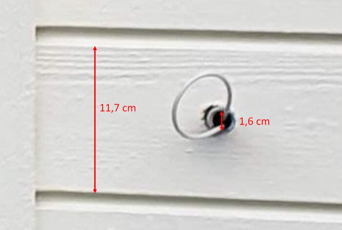 Grå slang med 16 mm innerdiameter ut ur vit panelvägg, markerad med mått (11,7 cm och 1,6 cm) för referens i husbyggesammanhang.
