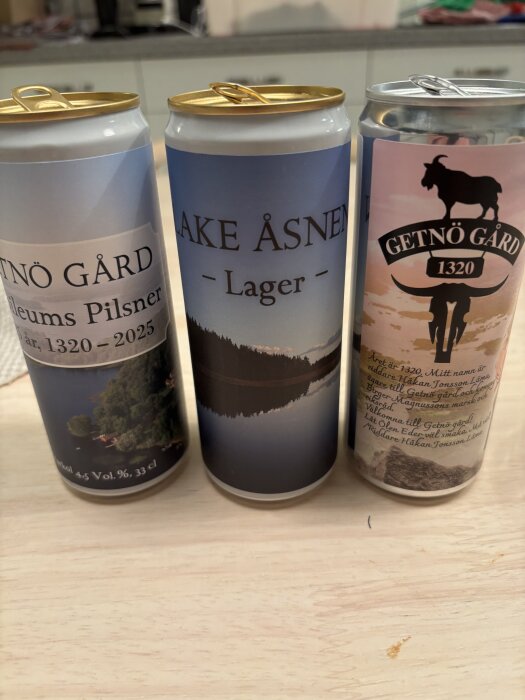 Tre ölburkar: Getnö Gård Jubileums Pilsner, Lake Åsnen Lager, och Getnö Gård IPA, står på ett bord, etiketter synliga.