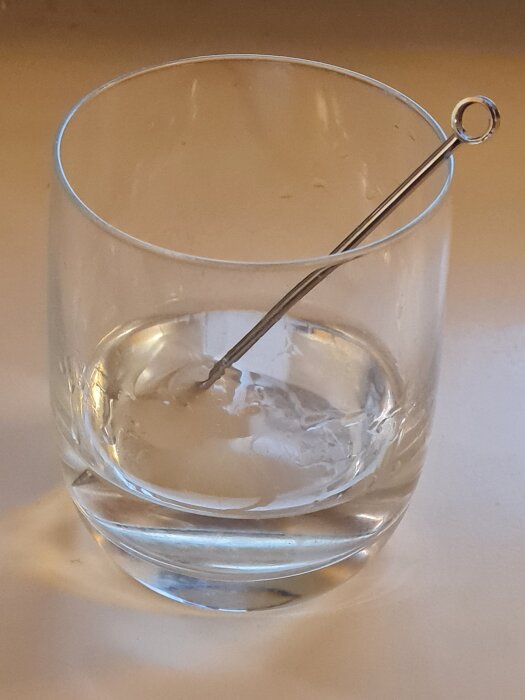 Tumblerglas med drycken gibson, två syltlökar och en cocktailpinne.