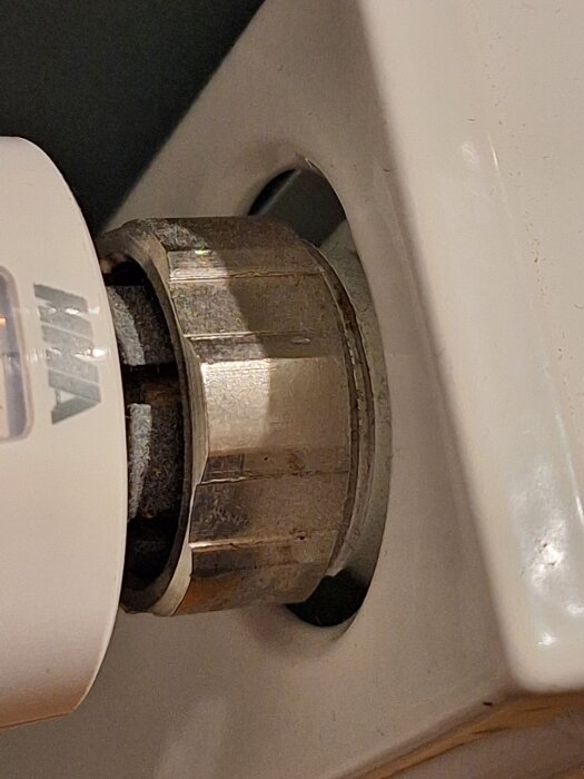 Radiatorventil med silvrig mutter på vit bakgrund.