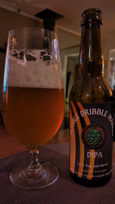 Flaska och glas med Double Dribble Mango DIPA från Lock Hop & Barrel i Sörping, med skummande öl.