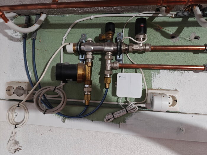 Rörsystem med nykopplade röda slangar och inspektionsbox, två avstängda ventiler och strömanslutningar på en vägg.