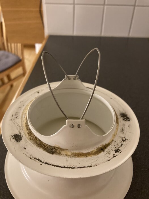 Tilluftsventil i plast med synlig monteringsram, placeras på ett bord. Ventilen har smuts och är delvis demonterad.