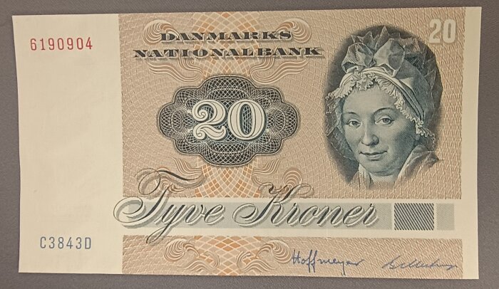 Dansk 20-kronorssedel med porträtt av kvinna och dekorativa mönster, texten "Danmarks Nationalbank" och serienummer synliga.