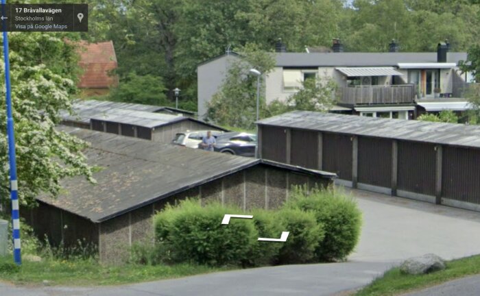 Radhusområde på Bråvallavägen med både gröna buskar och parkerade bilar framför byggnader omgivna av träd.