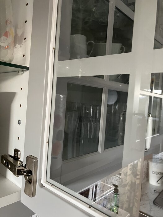 Öppen dörr till vitrinskåp; spikhuvuden synliga längs dörrkanten.