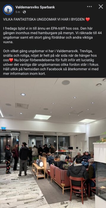 Ungdomar och vuxna i en banklokal pratar och sitter i soffor kring ett bord. Ljusa väggar, taklampor och en öppen spis syns i bakgrunden.