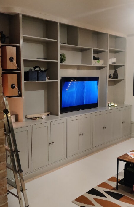 En hemgjord bokhylla med Ikeas Havsta som underdel och egengjord överdel i furu limfog, med belysning i överdelen och TV i mitten.