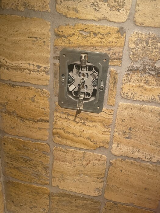 Eluttag på en vägg med gul tegel.