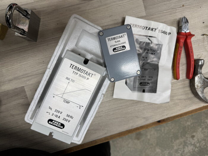 Termotakt-styrenhet från ASEA Skandia med kopplingsschema, en tång och en hammare på en träyta.