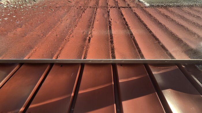 Profilerat entrétak och aluminiumpanel med en överlappning, med fokus på tätning mellan materialen.