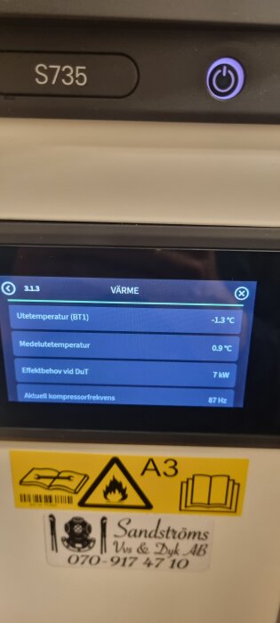 Display på en värmepump Nibe S735 visar temperaturdata: utetemperatur -1.3°C, medeltemperatur 0.9°C, effektbehov 7 kW, kompressorfrekvens 87 Hz.