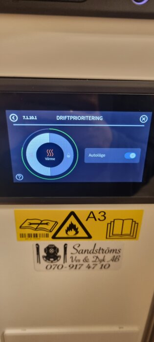 Skärmvisning av värmepumpens driftsprioritering i autoläge. Under skärmen syns varningstecken för eld och kontaktuppgifter för VVS-firma.