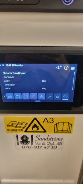 Display av värmepumpens gränssnitt som visar temperaturläge -1°C och smarta funktioner. Varningsetiketter och kontaktdetaljer på värmepumpen.