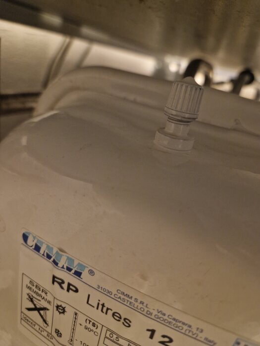 En vit tank med en ventilliknande komponent och etikett med specifikationer, inklusive "CIMM" och "12 liter".