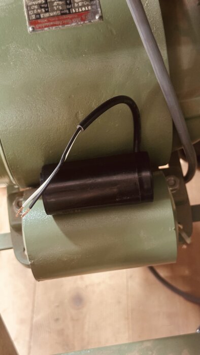 Ny kondensator monterad på Ulmia tallriksslipmotor, med synliga ledningar.