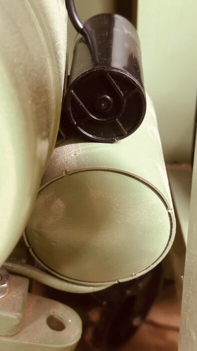 Ny, svart kondensator monterad på grön Ulmia tallriksslip, visar skillnad i storlek från gammal kondensator, båda synliga på bilden.