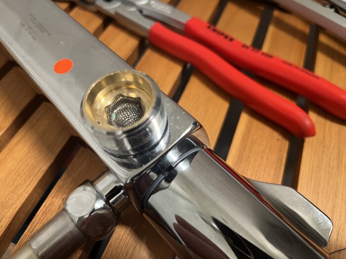 Kromad blanderanslutning med röd markering, omgiven av verktyg, på träbakgrund.