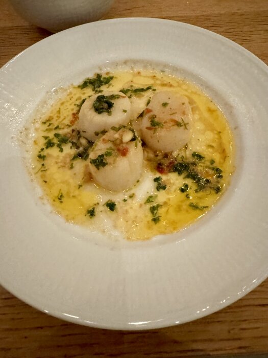 Tallrik med pilgrimsmusslor i smält smör, vitlök och persilja.