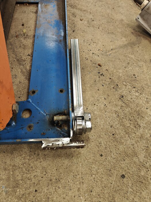 Hemmagjort bord med kullager och svetsade fyrkantsrör, stång och muttrar, visar ett hörn av konstruktionen på ett betonggolv.