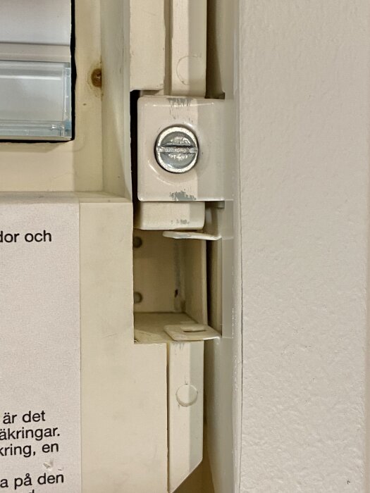 Gammalt inbyggt säkringsskåp utan gångjärn och lås, med en skruvad del synlig närmast kameran.