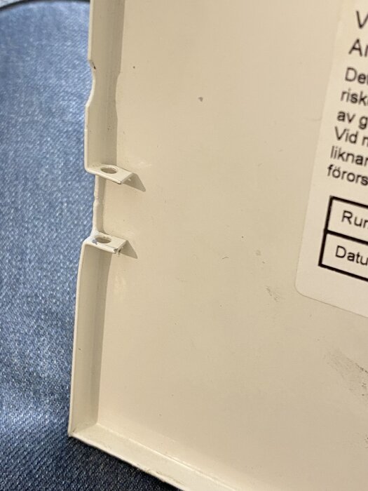 Ett vitt inbyggt säkringsskåp med borttagna gångjärn visas mot en mörk bakgrund.