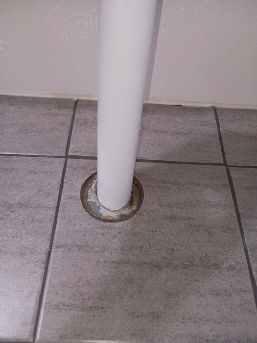 Avloppsrör från handfat med rörmanschett på kaklat golv, synligt limmad anslutning.