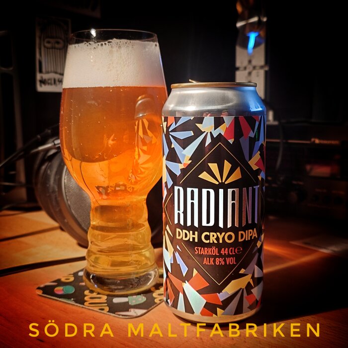 En ölburk och ett glas öl med skum på bordet, text på burken "RADIANT DDH CRYO DIPA", starköl 44 cl, alkohol 8% vol.