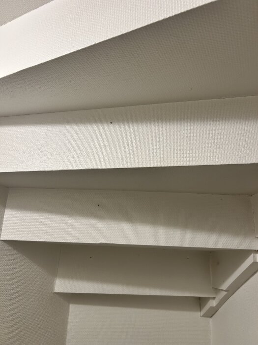 Trappa med flera vinklade väggar, redo för renovering och målningsarbete. Inlägget diskuterar spackling och skydd av dessa vinklar.