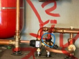 VVS-installation med rör och ventiler, markerad ventil i blå cirkel och röd markering i bakgrunden.