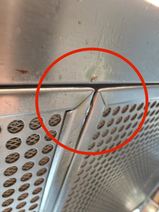 Närbild av rostfritt stålfläkt från IKEA Omnejd med fettfläckar och cirkel markerar ett område vid gallret.