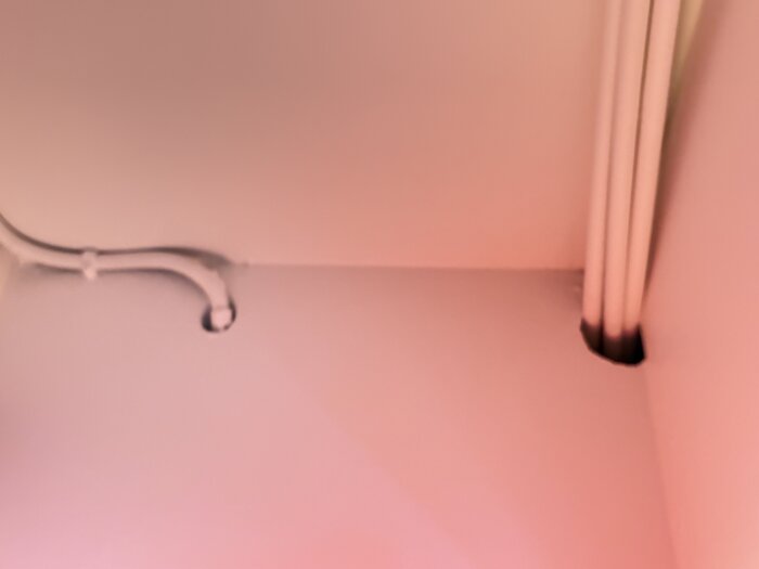 Rördragning genom vägg och tak, med rör i båda hörnen av bilden.