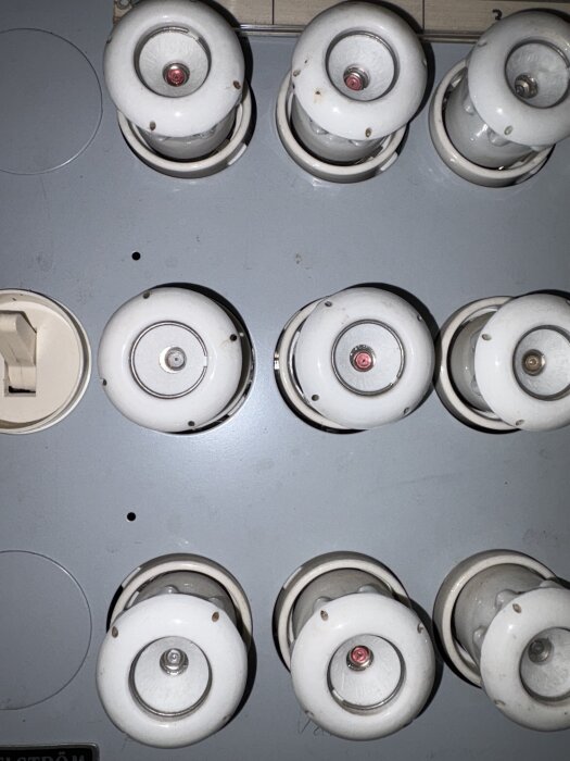 Elcentral med gamla porslinssäkringar i ett hem, potentiellt relaterad till problem med bastuaggregat och jordfelsbrytare.