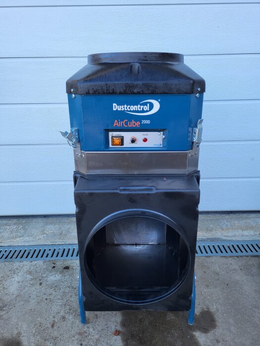 Luftrenare Dustcontrol AirCube 2000 i bra skick, saknar filter, står på betonggolv framför vit vägg.