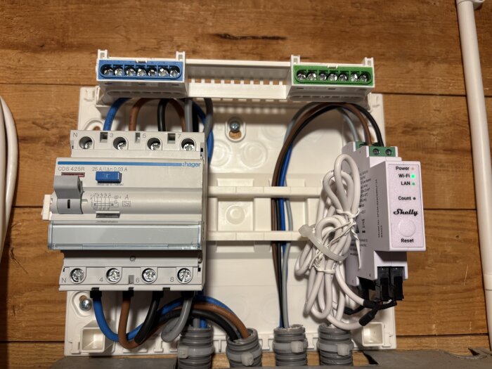 Elcentral med brytare och Shelly-enhet på trävägg, kablar organiserade med Wago-klämmor.