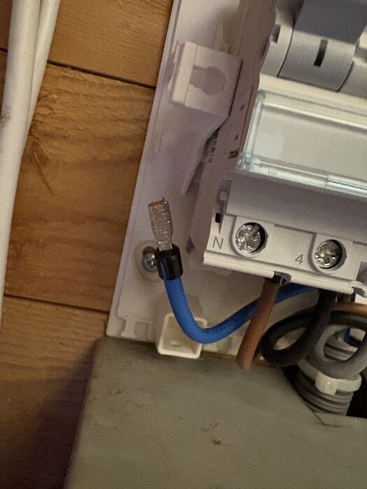 Elektrisk plint med blå och brun kabel; den blå kabeln har ett hölje på kardelen som inte passar i plinten.