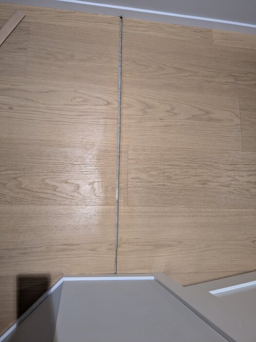 Springa mellan två golvbrädor i trä, som behöver breddas för att passa en T-list.