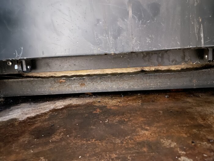 Botten av en Biomatic+20 panna med kallvattenläckage synligt och svagt nedbuktad plåt.