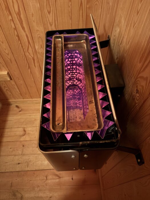 En bastuugn med lila stenar på en träbeklädd bastugolv.