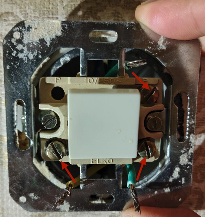 Eluttag med gul och grönblå kablar anslutna till gammal strömbrytare med märket Elko, pilar pekar mot skruvar för anslutningar.