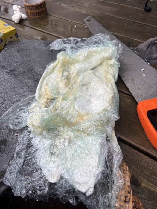 Plastfolie täcker ofullständigt härdat fogskum, med träbord och verktyg i bakgrunden.