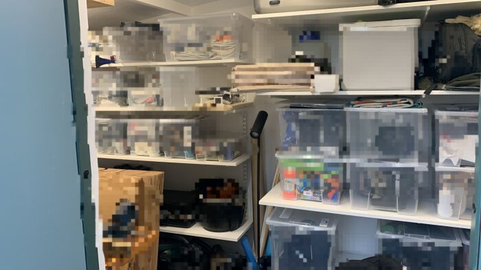 Hylla i ett förråd med Elfa-system, fylld med plastlådor och lådor. Fråga om de räknas som fast egendom vid husförsäljning.